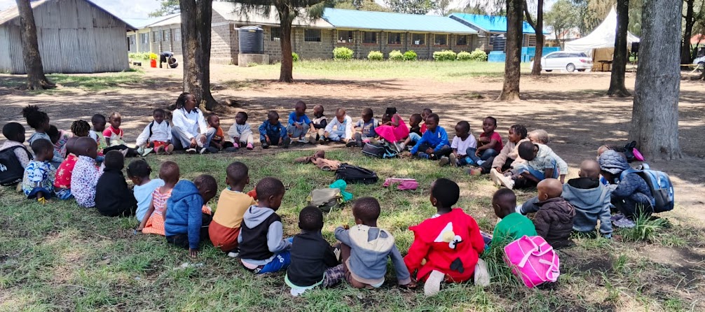 A CAN facilitator with children and families in an outdoor circle